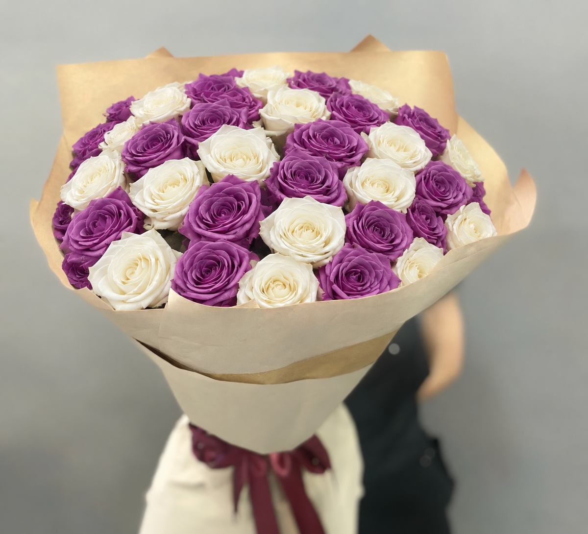 Wrapped bouquet of purple and white roses